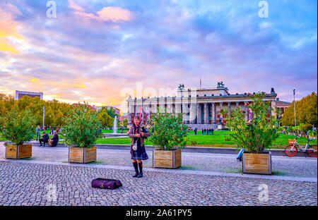 Berlino, Germania - 3 ottobre 2019: La zampogna musicista di strada in Highland dress giocando al Parco Lustgarten durante twilights, il 3 ottobre in Berl Foto Stock