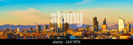 Vista aerea di Milano skyline al tramonto con le montagne delle Alpi in background. Foto Stock