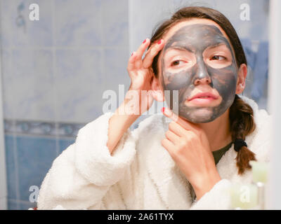 La ragazza è la cura per il viso. Cosmetici maschera nera. Una donna porta la bellezza per il suo volto si sbarazza di punti neri con una maschera nera. La donna nel Foto Stock