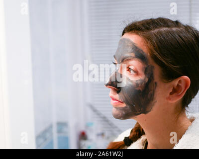 La ragazza è la cura per il viso. Cosmetici maschera nera. Una donna porta la bellezza per il suo volto si sbarazza di punti neri con una maschera nera. La donna nel Foto Stock