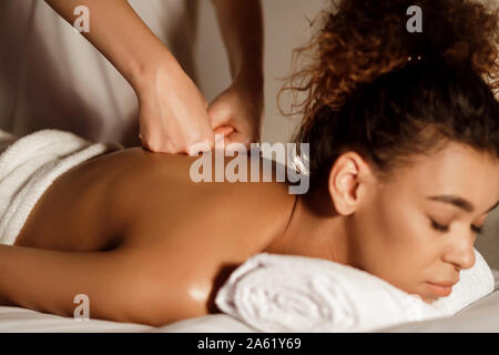 Massaggiatore con le mani in mano premendo giovane donna con la schiena, primo piano Foto Stock