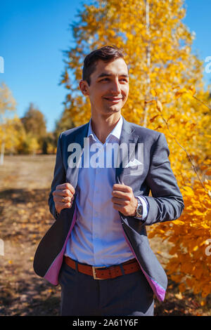 Maschio moda autunno. Uomo bello indossare tuta grigio e accessori esterni. Ritratto di giovane ragazzo in abiti eleganti Foto Stock