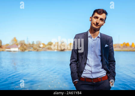 Maschio moda autunno. Uomo bello indossare tuta grigio e accessori esterni. Ritratto di giovane ragazzo in abiti eleganti Foto Stock
