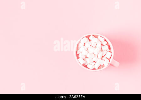 Tazza di cioccolata calda e marshmallows su una rosa di sfondo color pastello. Appartamento laico, vista dall'alto. Foto Stock