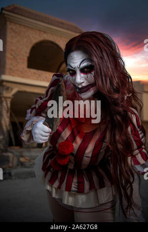 Un ritratto di un arrabbiato pazzo clown ragazza in casa di caccia. Concetto di Halloween tema Foto Stock