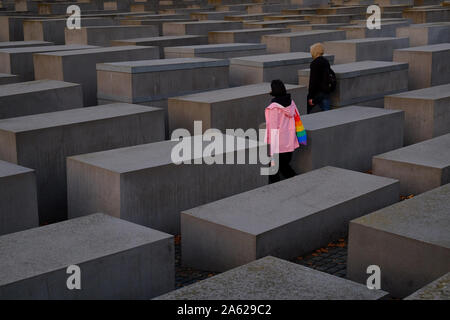 Berlin, Berlin, Germania. 23 Ott, 2019. I visitatori possono esplorare il monumento agli ebrei assassinati d'Europa (tedesco: Denkmal fÃ¼r die ermordeten Juden Europas), noto anche come il Memoriale dell'Olocausto (tedesco: Holocaust-Mahnmal) durante il tramonto nel centro di Berlino. Progettato da architetto Peter Eisenman, il monumento è composta da 2711 rettangolare di blocchi di calcestruzzo, stabiliti in una formazione a griglia. Credito: Jan Scheunert/ZUMA filo/Alamy Live News Foto Stock