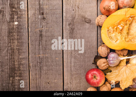 In autunno la disposizione dei raccolti stagionali con foglie colorate. Vista dall'alto di verdura e frutta come mele, zucca, noci, cipolle. Copia dello spazio. Foto Stock