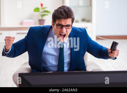 Il businesman guardando la tv in ufficio Foto Stock