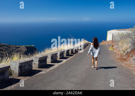 Ragazza cammina in mezzo alla strada costiera Foto Stock