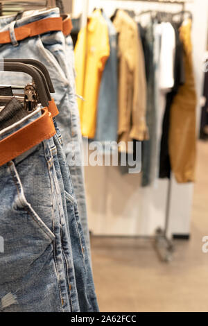Jeans blu su un appendiabiti in primo piano una dressing room in background. Memorizzazione di cose. Foto Stock