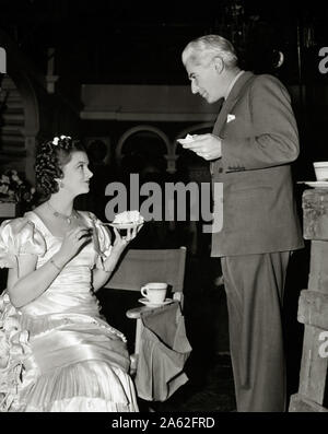 Myrna Loy con il regista John Stahl, mangiare la torta sul set del film ''Parnell' (1937) MGM Riferimento File # 33848-910THA Foto Stock