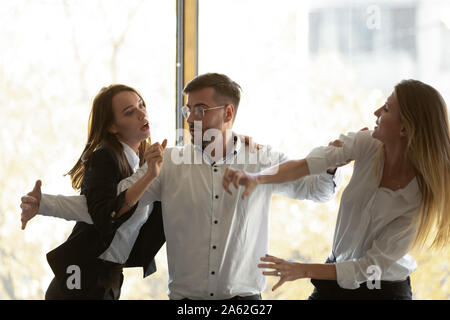 Collega di sesso maschile distanziate aggressivo donne business combattimenti in ufficio Foto Stock