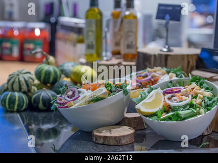 Salad bar con coppe con cipolle e limone rucola e zucca in background così come olio di oliva e altre salse Foto Stock