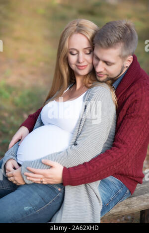 Bella donna incinta con il marito passeggiate nel parco di autunno Foto Stock