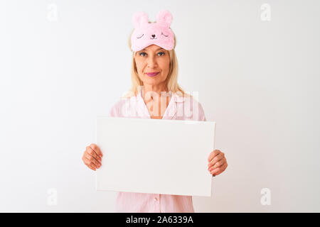 Medioevo donna che indossa la maschera del sonno pigiama azienda banner isolato su sfondo bianco con un fiducioso espressione sul viso intelligente pensare grave Foto Stock
