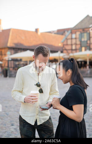 Uomo che mostra lo smartphone donna in città Foto Stock