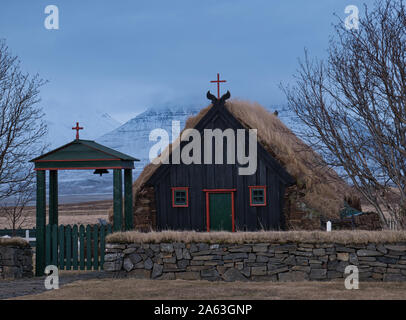 L'entrata di una piccola chiesa di torba in Islanda con le montagne sullo sfondo Foto Stock