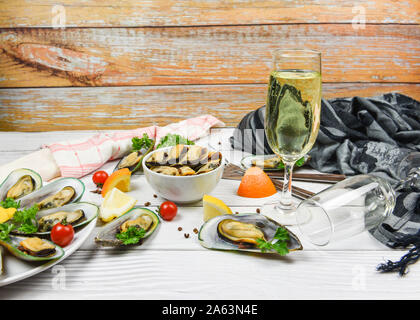 Le cozze al vapore e il bicchiere di vino servito in tazza di salsa di pesce delizioso sul tavolo da pranzo il ristorante / Cozze con erbe aromatiche con limone prezzemolo nella tabella Foto Stock