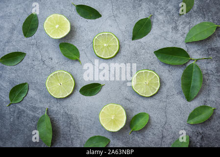 Laici flat top view fettine di lime con foglie di lime su sfondo scuro Foto Stock