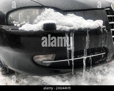 Un ghiaccioli con neve sui fari di automobile. Foto Stock