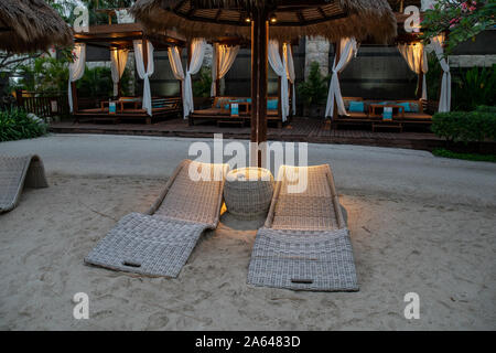 In vimini rilassanti sedie reclinabili dalla piscina dell'hotel dopo il tramonto Foto Stock