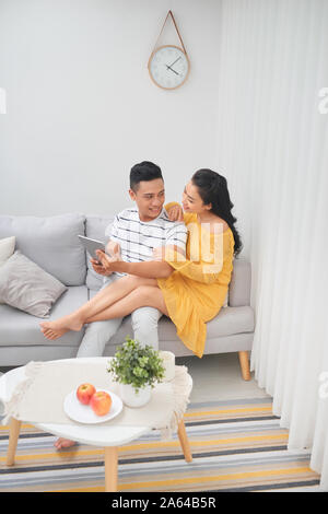 Coppia giovane in un momento di relax a casa di lusso con i computer tablet lettura in salotto sul divano del lettino. Foto Stock