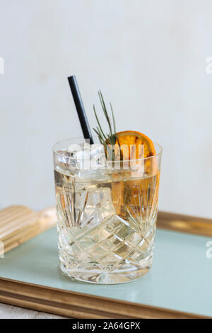 Il gin tonic guarnito con carbonizzati arancio e lavanda, su un tavolo Foto Stock