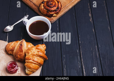 Caffè e cornetti freschi sulla tavola nera Foto Stock