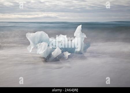 Piccolo ghiacciaio iceberg nel surf, una lunga esposizione, Breidarmerkursandur, vicino Joklusarlon, Sud Islanda Islanda Foto Stock