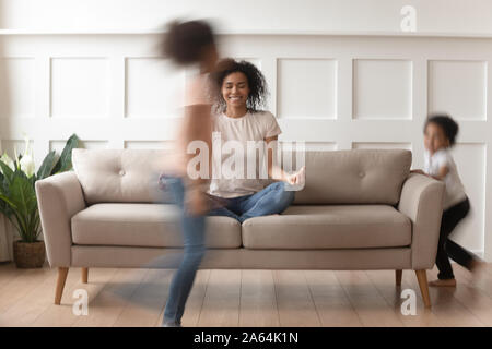 Felice mom nero la pratica dello yoga con i bambini attivi intorno Foto Stock