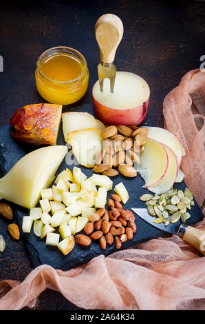 Un assortimento di dolci di formaggio a pasta filata, Provolone in varie forme e dimensioni su sfondo di legno, suluguni, pigtail, Caciocavallo con pomodori a Foto Stock