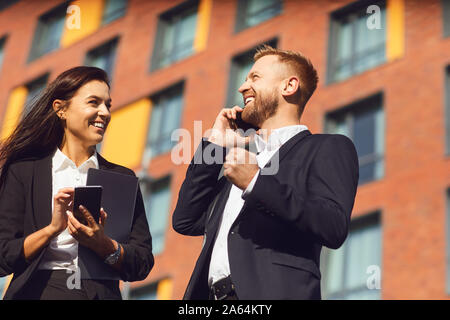 Gli imprenditori sorridente parlando al telefono sullo sfondo di un edificio aziendale Foto Stock