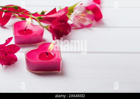 Due a forma di cuore ad candele sul bianco tavolo in legno Foto Stock