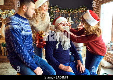 La famiglia felice in casa con albero di natale festeggia il Natale. Foto Stock