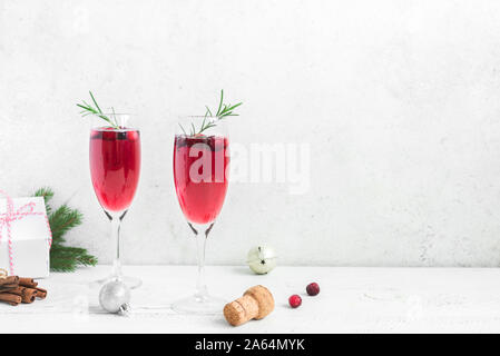 Natale mirtillo rosso mimosa con rosmarino su sfondo bianco, copia dello spazio. Cocktail con champagne per la mattina di Natale. Foto Stock