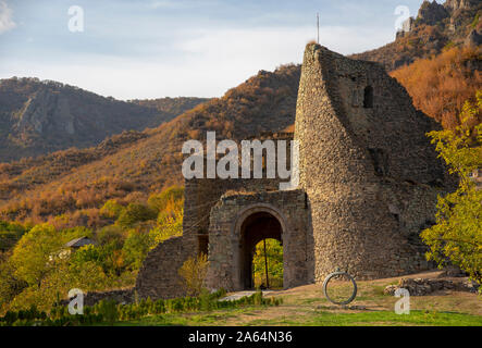 Rovinato mattone vecchia torre, parete e gate contro lo sfondo delle montagne e del cielo. Foto Stock