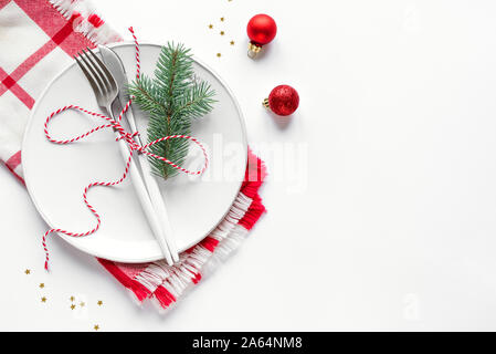 Tavola di natale con impostazione del ramo di abete e ornamenti di colore rosso su bianco, laici piana, copia dello spazio. Cena di Natale, festa design, concetto - tabella di impostazione con Foto Stock