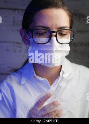 Close up di un infermiere. Medico infermiere, dietro la maschera di un chirurgo. Closeup ritratto di una giovane donna caucasica modello indossando occhiali nero Foto Stock