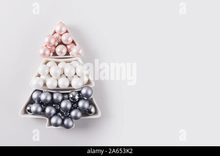 Albero di Natale fatto di argento sfere pastello su sfondo grigio. Composizione di natale. Appartamento laico, vista dall'alto, copia dello spazio. Messaggio di saluto festivo card. Felice Anno Nuovo Foto Stock