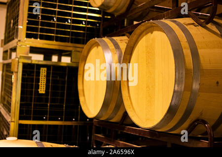 American botti di rovere per l'affinamento e la maturazione del vino in una cantina impilati su scaffalature metalliche Foto Stock