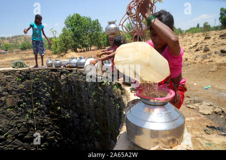 Le donne di raccogliere l'acqua dal pozzetto a Dhakne village, Shahapur Thane Maharashtra, India, Asia Foto Stock