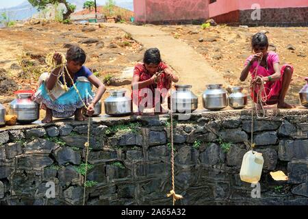I bambini a raccogliere acqua dal pozzo, Dhakne village, Shahapur Thane Maharashtra, India, Asia Foto Stock