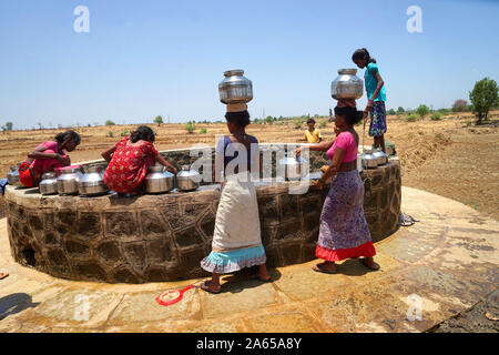 Donne rurali che raccolgono l'acqua dal pozzo del villaggio di Dhakne, Shahapur Thane Maharashtra, India, villaggio asiatico indiano Foto Stock