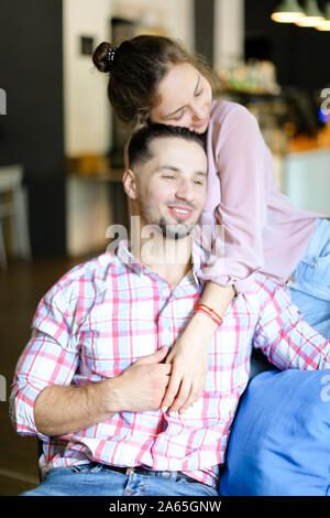 Giovane donna seduta con l uomo e avvolgente. Foto Stock
