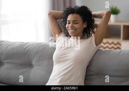 Sorridente donna nera rilassarvi sul lettino a casa Foto Stock