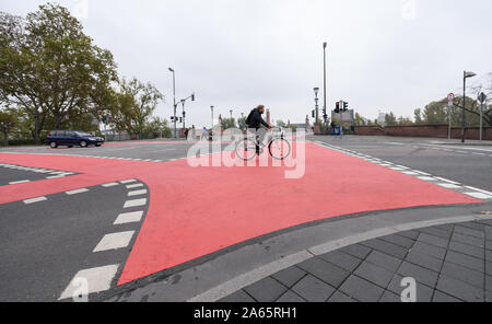 24 ottobre 2019, Assia, Frankfurt/Main: un uomo che cavalca una bicicletta su una marcata in rosso il percorso del ciclo su un incrocio. Il consiglio della città ha deciso di rendere Francoforte una bicicletta città. Foto: Sila Stein/dpa Foto Stock