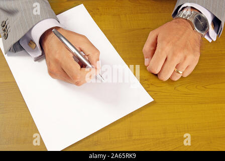 Persona vestita in tuta la scrittura su carta a tavola Foto Stock