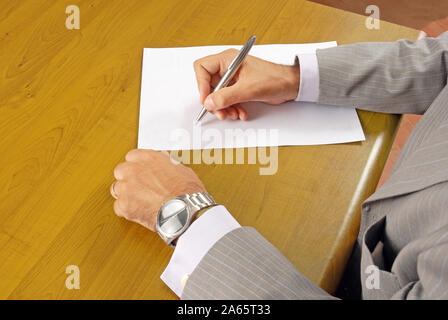 Persona vestita in tuta la scrittura su carta a tavola Foto Stock