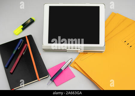 Forniture per ufficio costituito da tablet con tastiera frontale, marcatore fluorescente, il rosso e il blu marcatori, penna moderna, blocco note appiccicose e note book con o Foto Stock