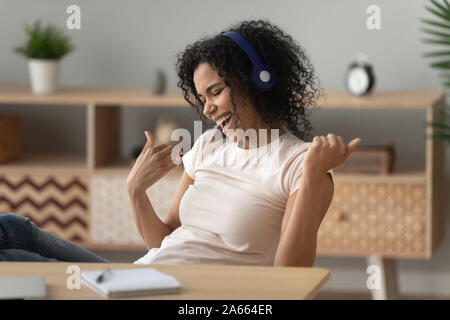 Eccitato nero ragazza divertirsi ascoltando musica in cuffia Foto Stock